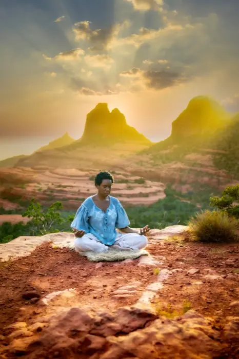 Yolessa seated in meditation on red rock at sunrise